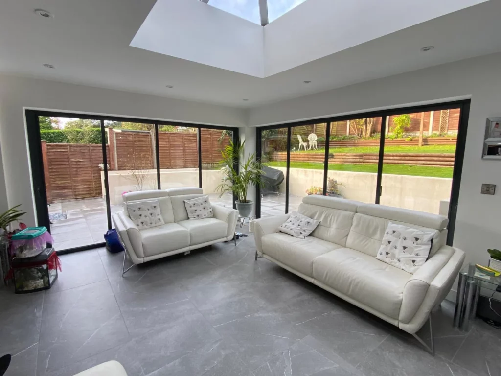 Modern minimal living room area with large bifold glass patio doors and white furniture