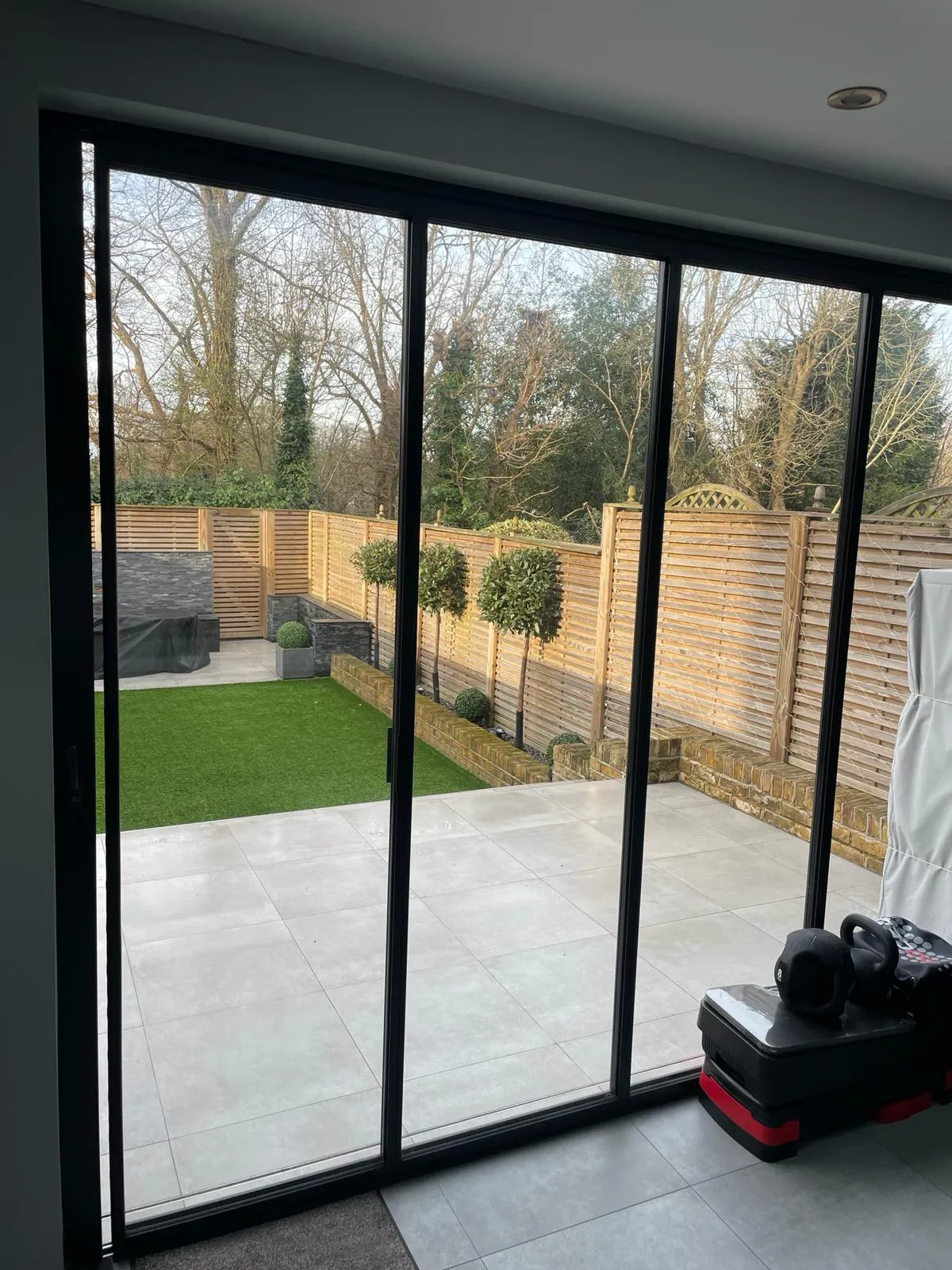 Looking onto a patio and garden through black bifolding doors